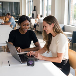Two women working together on a laptop with a MIND MELT tin on the table